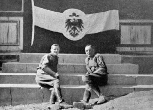 South African officers pose with a captured German flag in Windhoek (present day Namibia), 1915. Image in public domain.