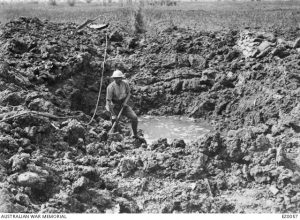 A soldier beside a crater made by a German minenwerfer (trench mortar) bomb, Cordonnerie Farm, France, 30 May 1916. Image courtesy Australian War Memorial.
