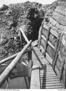 Section of the Australian front line at Gueudecourt showing sandbag reinforcement, duckboards and timber bridge over flooding. Image courtesy Australian War Memorial.